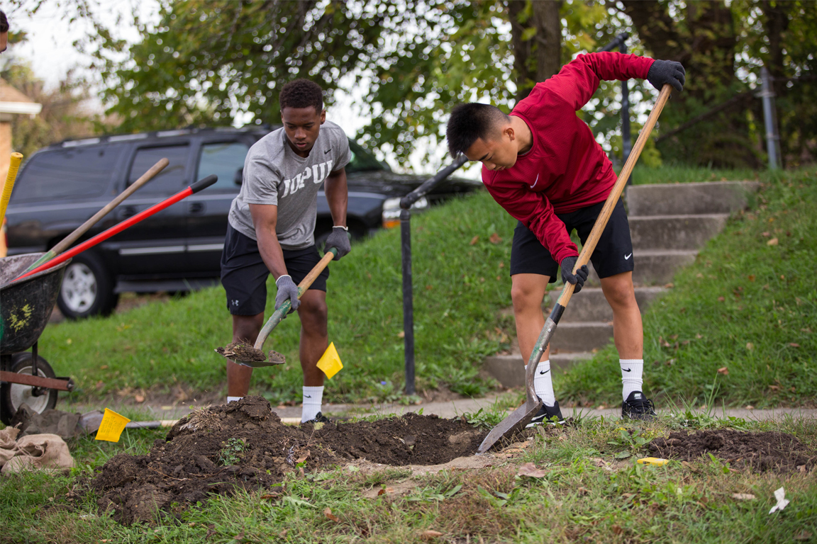Students shoveling dirt as part of a community service activity.
